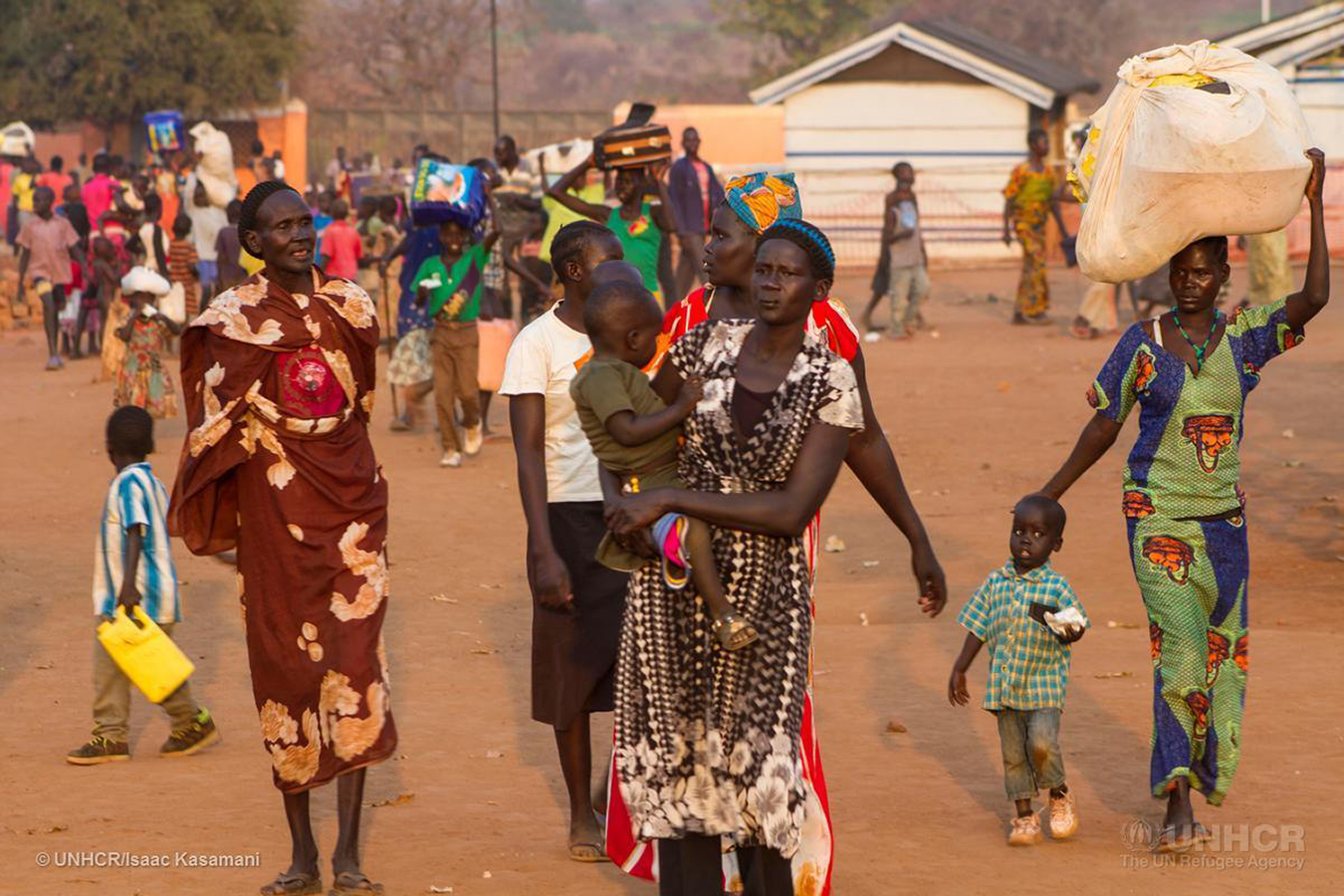 Newly arrived South Sudanese refugees carry their belongings at the Nyumanzi reception center in Adjumani, a district in northern Uganda. Since the first week of January 2016, Uganda has seen an influx of 4,587 refugees from the neighboring war-torn country of South Sudan. | Photo courtesy © UNHCR/Isaac Kasamani