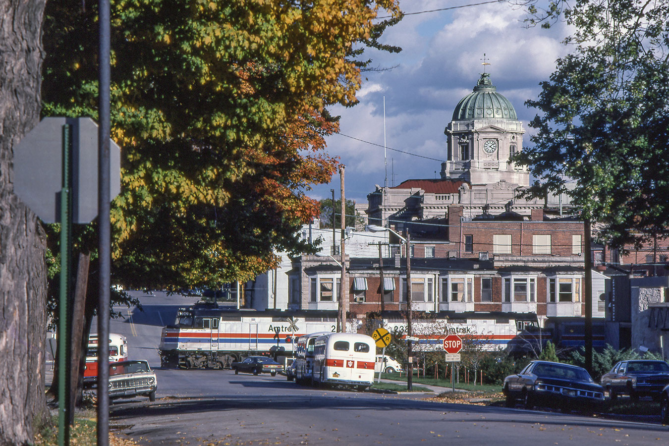 "Monroe County Courthouse": A northbound Amtrak "Floridian" makes a station stop in Bloomington. We are looking eastward along West 6th Street, with the iconic Monroe County Courthouse beyond. The building just behind the train now houses Janko’s Little Zagreb. The date of the photograph is October 16, 1977. | Photo by Richard Koenig