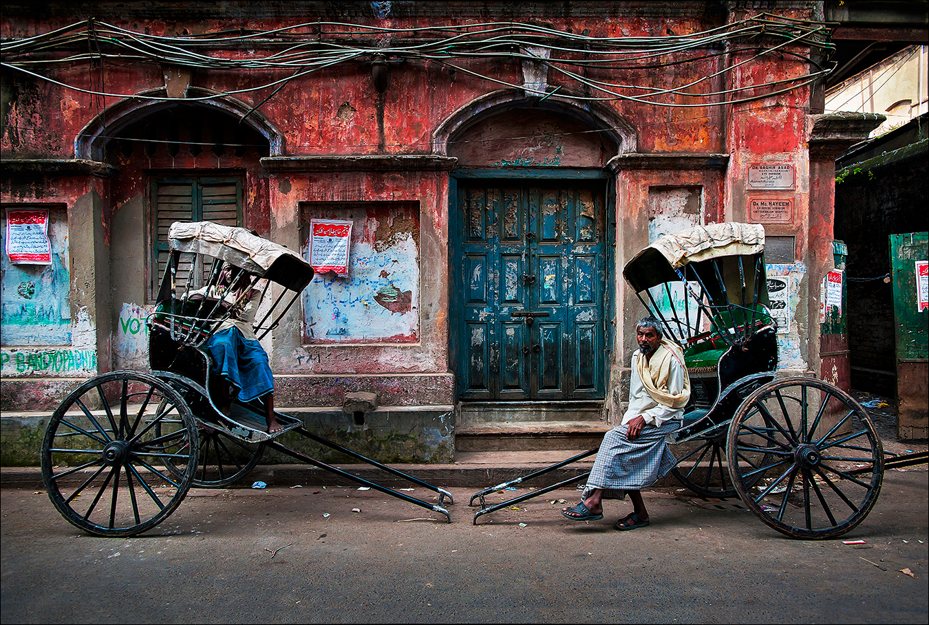 As if in a scene from the early twentieth century, rickshaw-pullers rest on a backstreet in Calcutta, now renamed Kolkata, capital of the Indian state of West Bengal. The city's some six thousand licensed rickshaw drivers are often called "human horses" and generally earn less than five dollars a day navigating the city's crowded and sometimes flooded streets. | © Steve Raymer / National Geographic Creative