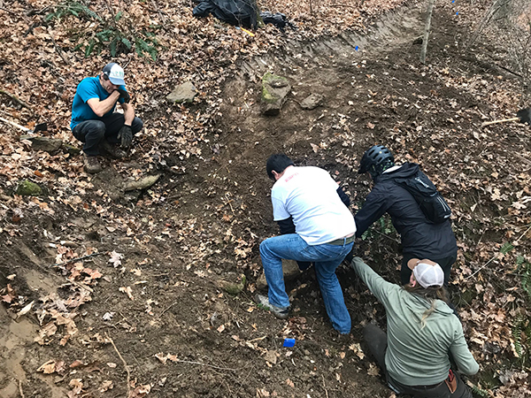 Members of the Hoosier Mountain Bike Association dig out a large rock during their work on Crooked Creek Loop. | Photo by Jesse Smith