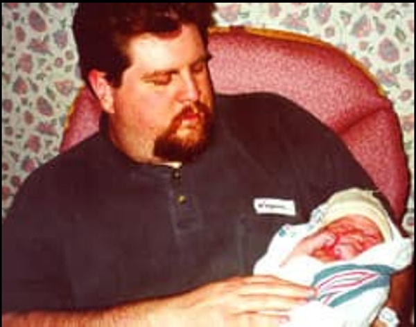 Troy sits with his newborn daughter. | Courtesy photo