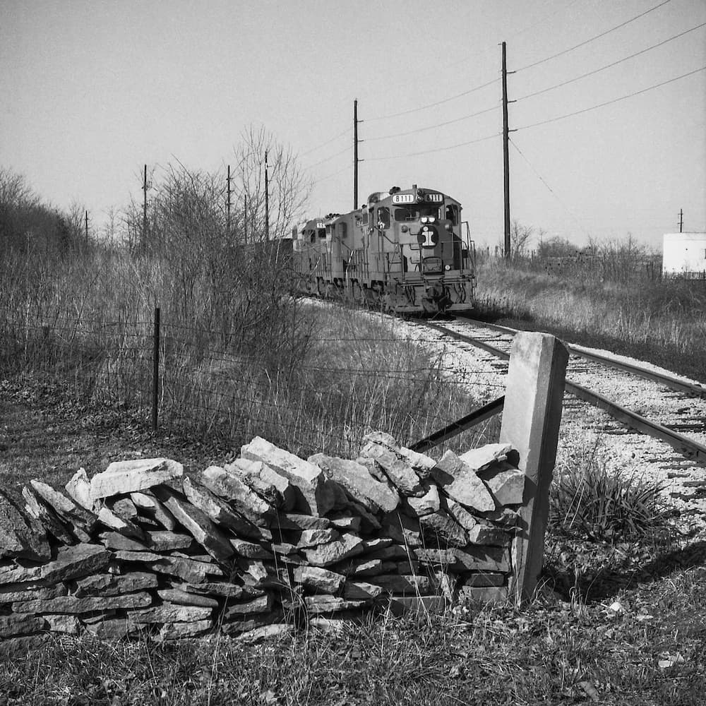 This photo was taken by Limestone Post contributor Richard Koenig, the Genevieve U. Gilmore Professor of Art at Kalamazoo College in Michigan. Growing up in Bloomington, Richard often photographed trains throughout the area. Some of those photos became the focus of his essay “Tracks Through Time: The Trains of 1970s Bloomington,” which is one of our most-viewed stories of all time. This southbound train is shown on its route between Morgantown and Bloomington, near Mt. Gilead Road and State Road 45 on March 25, 1977. Richard sent us this photo because of the limestone post in the foreground. | Photo by Richard Koenig
